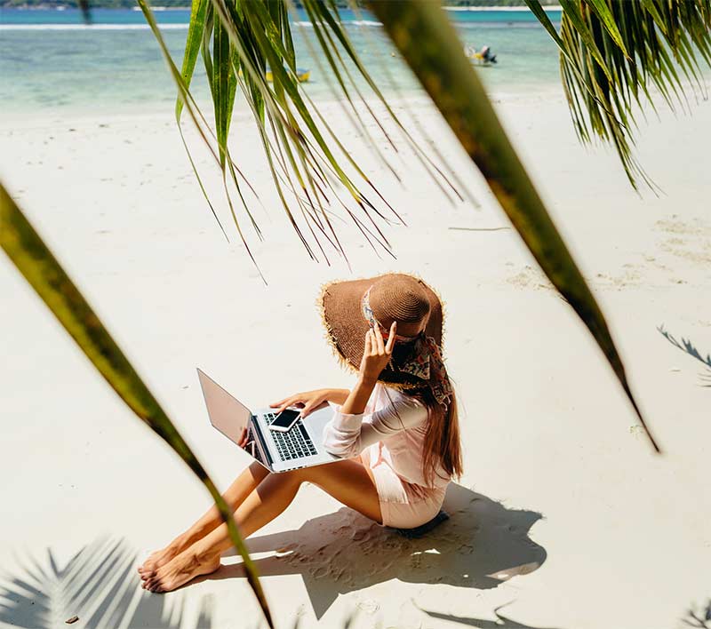 woman on a beach with laptop